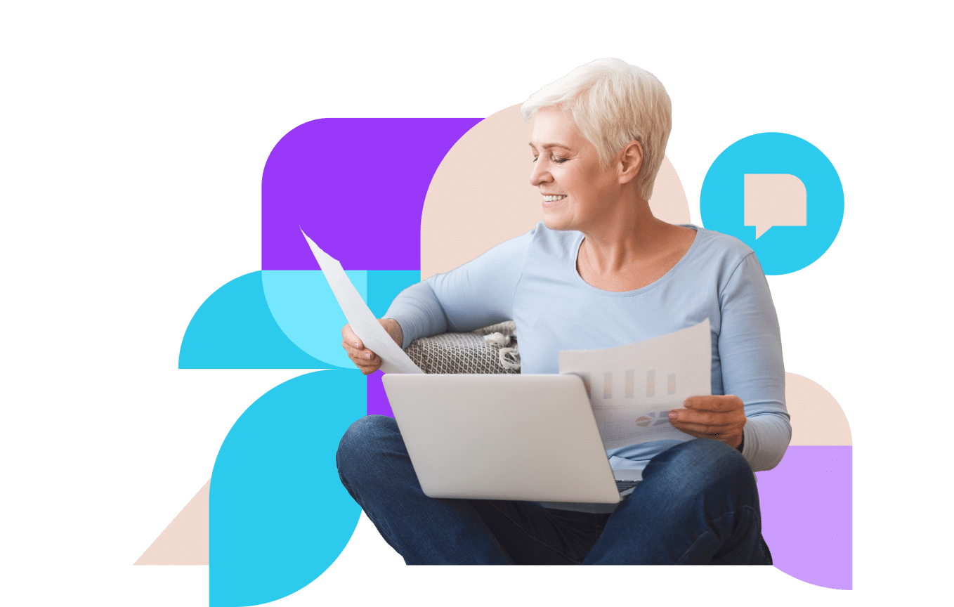 Older businesswoman looks at graphs on paper with laptop in her lap smiling