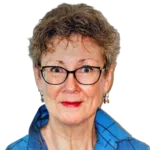 A woman with short, wavy hair and glasses is looking directly at the camera. She is wearing a blue collared shirt and small earrings. The background is removed, making her the focal point of the image.