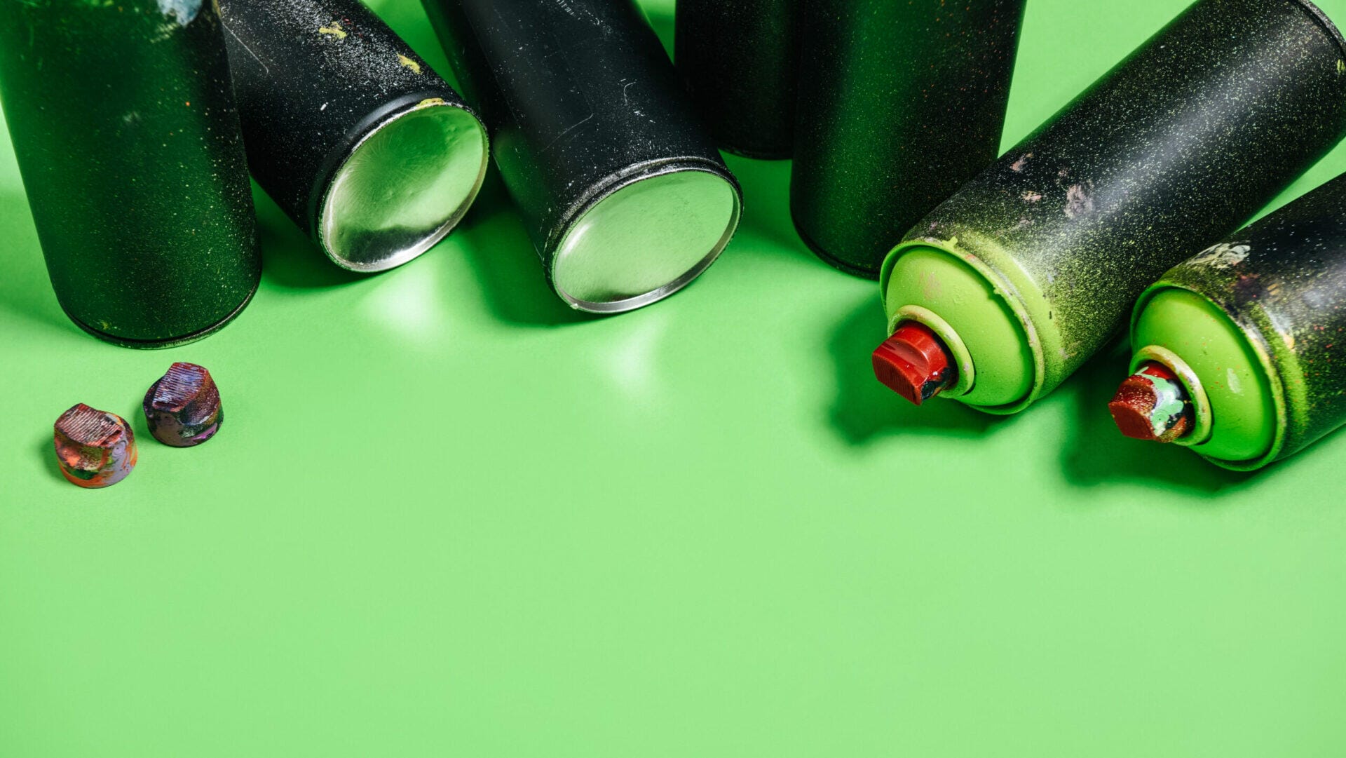 close up view of green spray paint cans - Greenwashing aims to entice green-conscious consumers into supporting a product or service, even if it isn’t necessarily eco-friendly.  