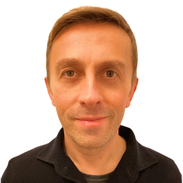 Portrait of a man with short brown hair and light complexion, looking directly at the camera with a neutral expression. He is wearing a black collared shirt and the background is plain white.
