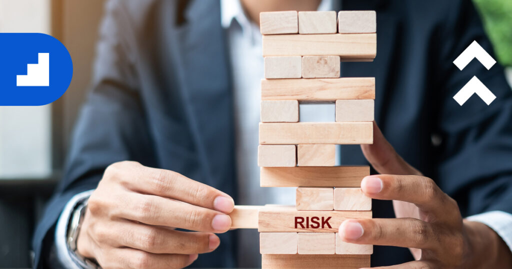 Close-up of a person in a business suit carefully pulling a wooden block from a Jenga tower, symbolizing managing business risks and turning them into growth opportunities.