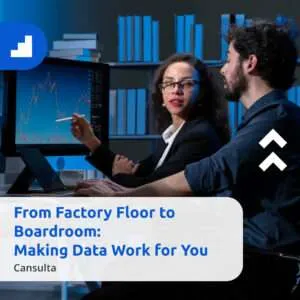 A woman and a man analyzing data on large monitors in a modern office. In front of them, a banner reads: ‘From Factory Floor to Boardroom: Making Data Work for You — Cansulta.’