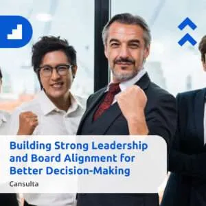 A group of five business professionals standing together indoors, smiling confidently and raising their fists in a gesture of strength and unity. Blue geometric branding elements appear in the upper corners. Text on the image reads: ‘Building Strong Leadership and Board Alignment for Better Decision-Making – Cansulta.’