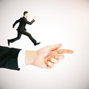 A businessman in a suit running across a giant pointing finger, illustrating the concept of guidance and direction.