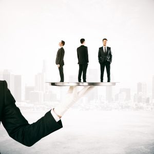 A gloved hand holds a silver platter with three miniature businessmen against a city skyline