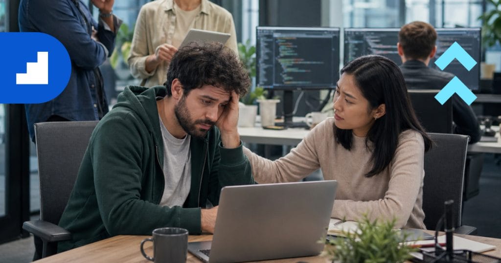 A software engineer experiencing workplace burnout in a modern tech office, being supported by a colleague. This image illustrates the mental health challenges in engineering teams.